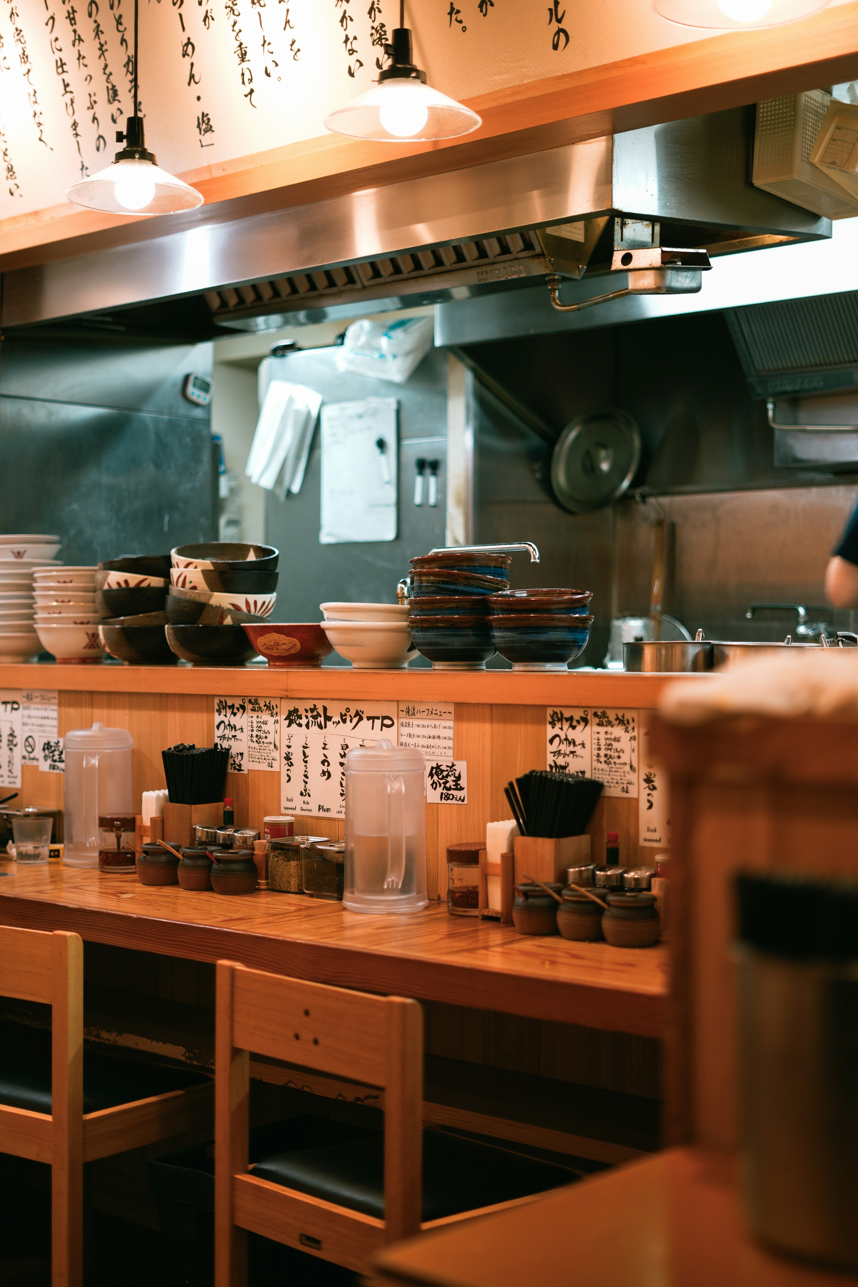 The wooden ramen counter with stacked bowls and stools, ready for service