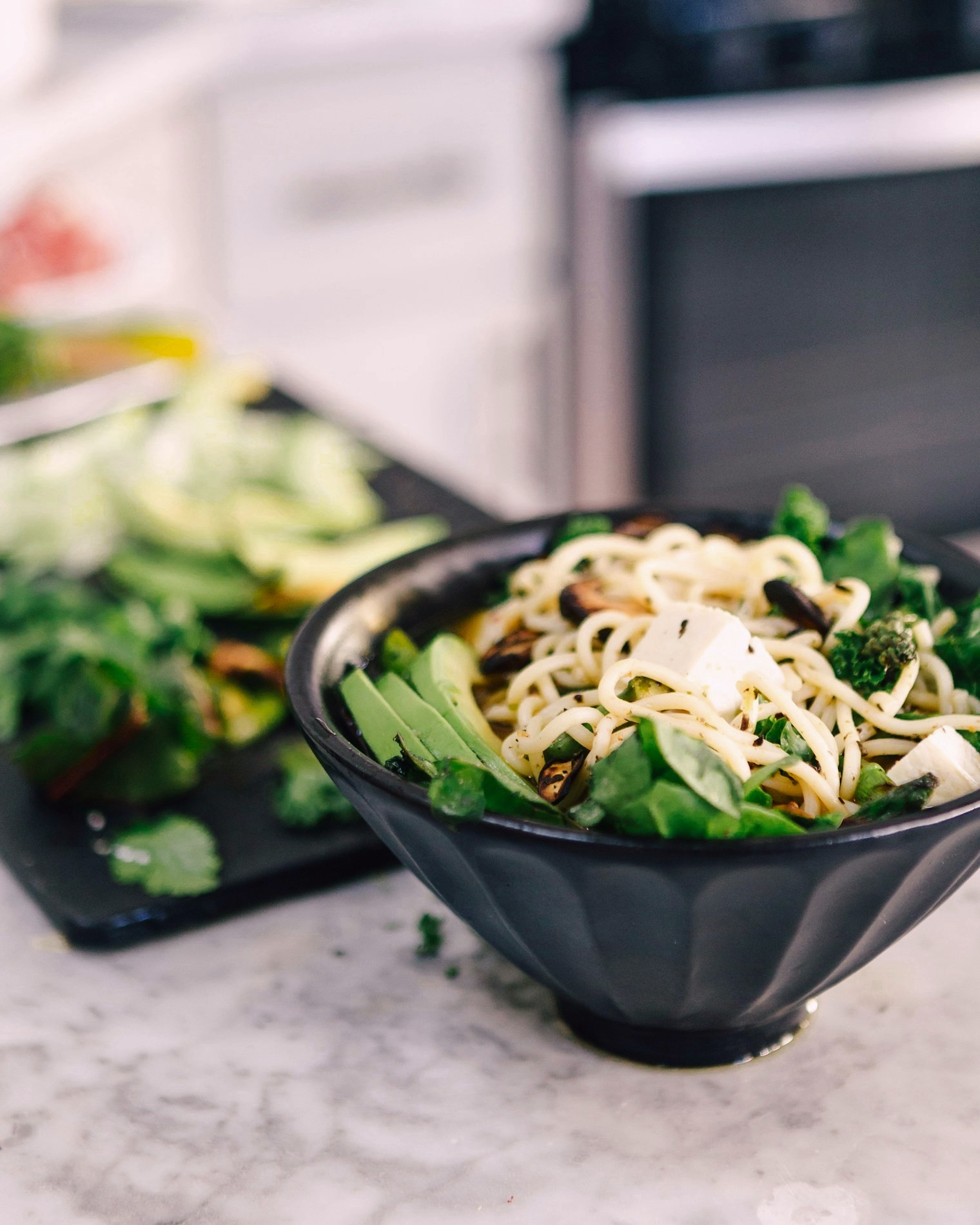 A vegan bowl of noodles with greens, tofu and sesame