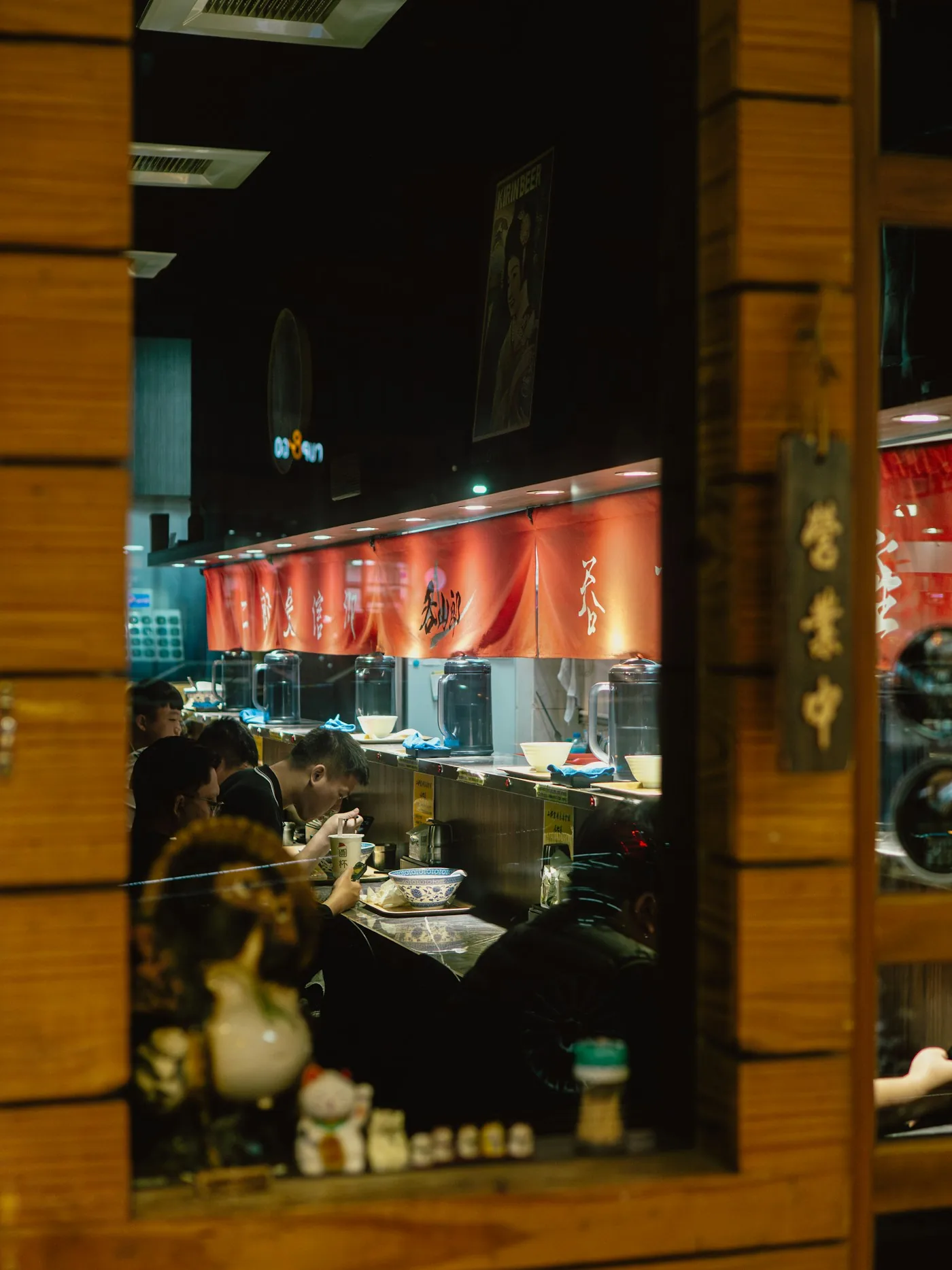 Diners at a ramen counter at night under red banners