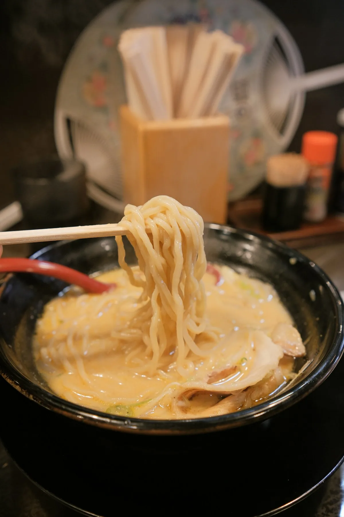 Thick noodles lifted from a cloudy white tonkotsu broth
