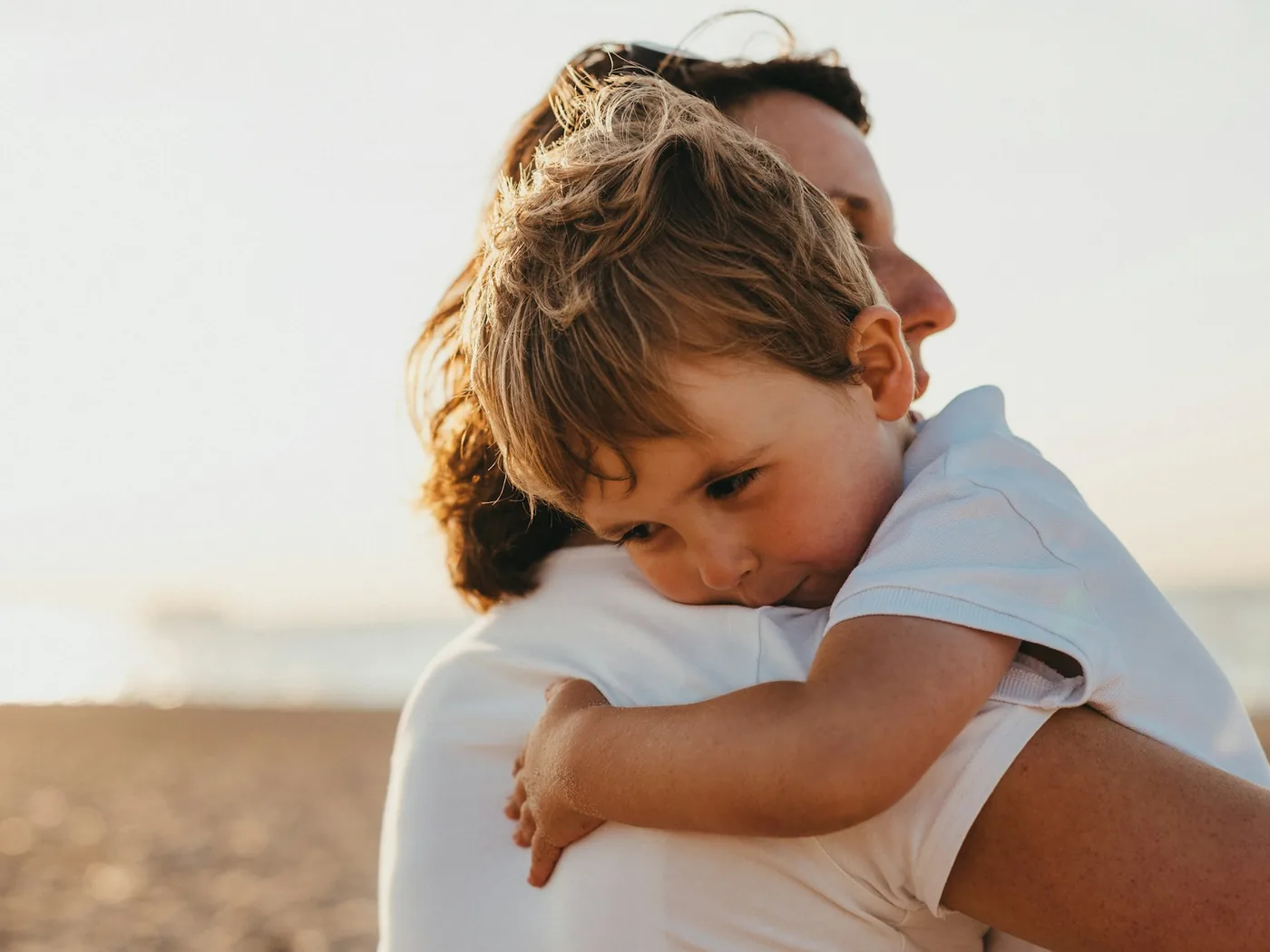 Parent holding a smiling child close in warm evening light