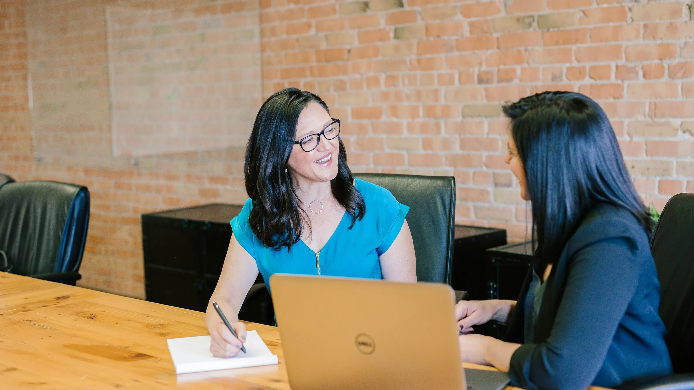 Immigration attorney taking notes while a client explains her situation across a desk
