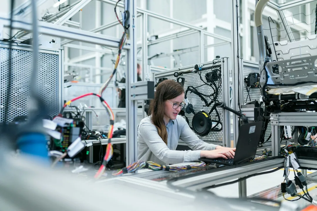 Engineer working at a laptop beside test equipment in a bright lab