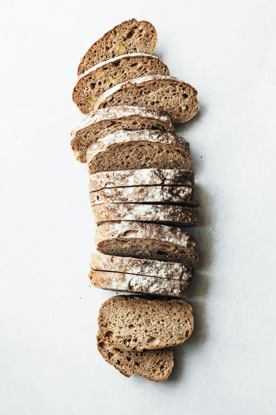Thin slices of seeded rye bread laid out in a line on white