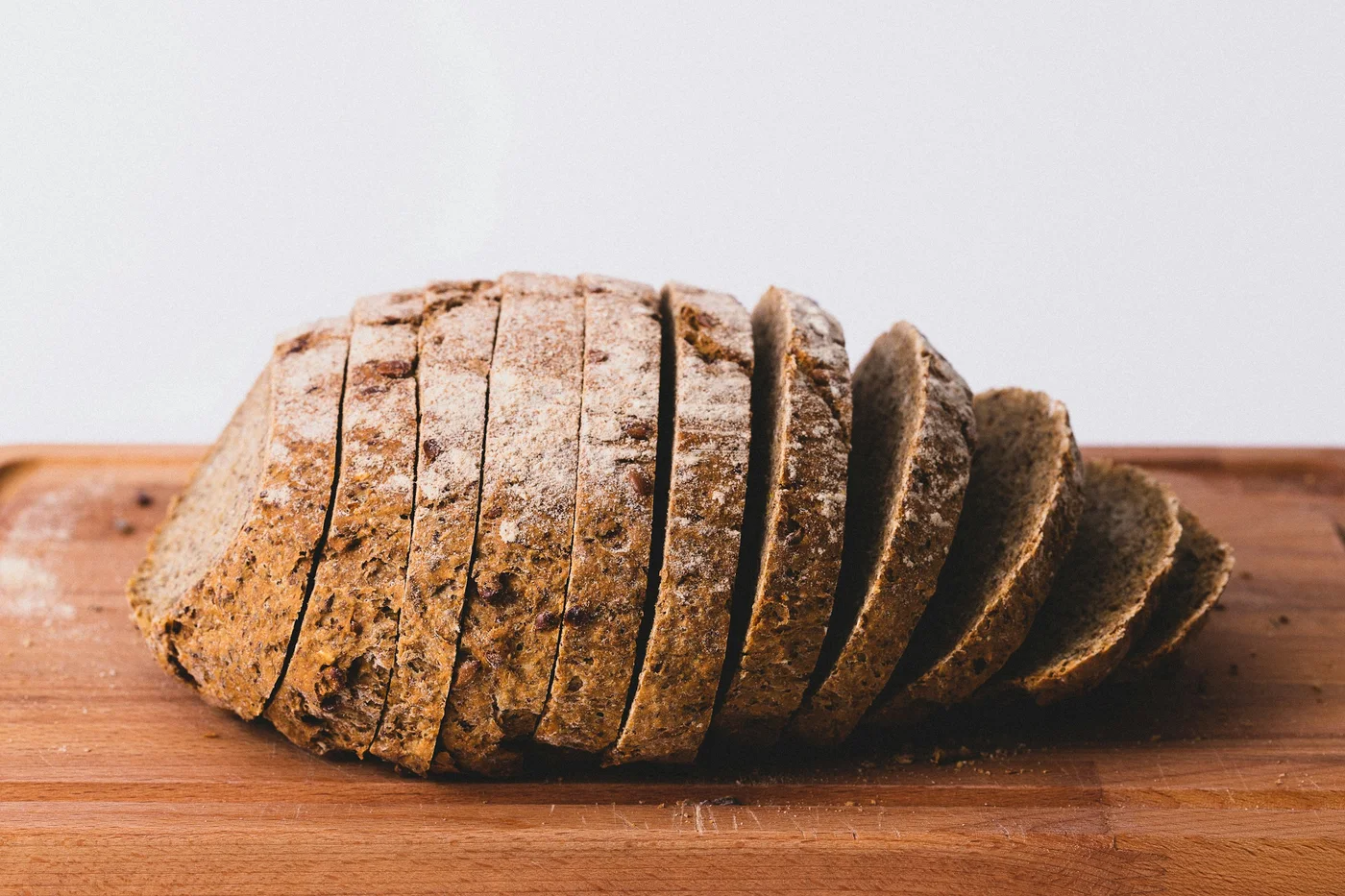 A dark rye loaf cut into thick slices on a wooden board