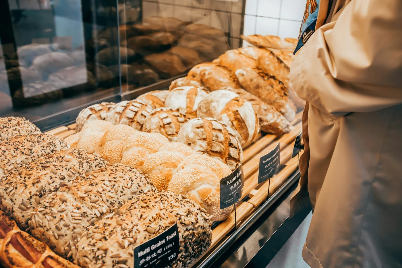 Seeded sourdough loaves and buns in the glass counter as a customer chooses