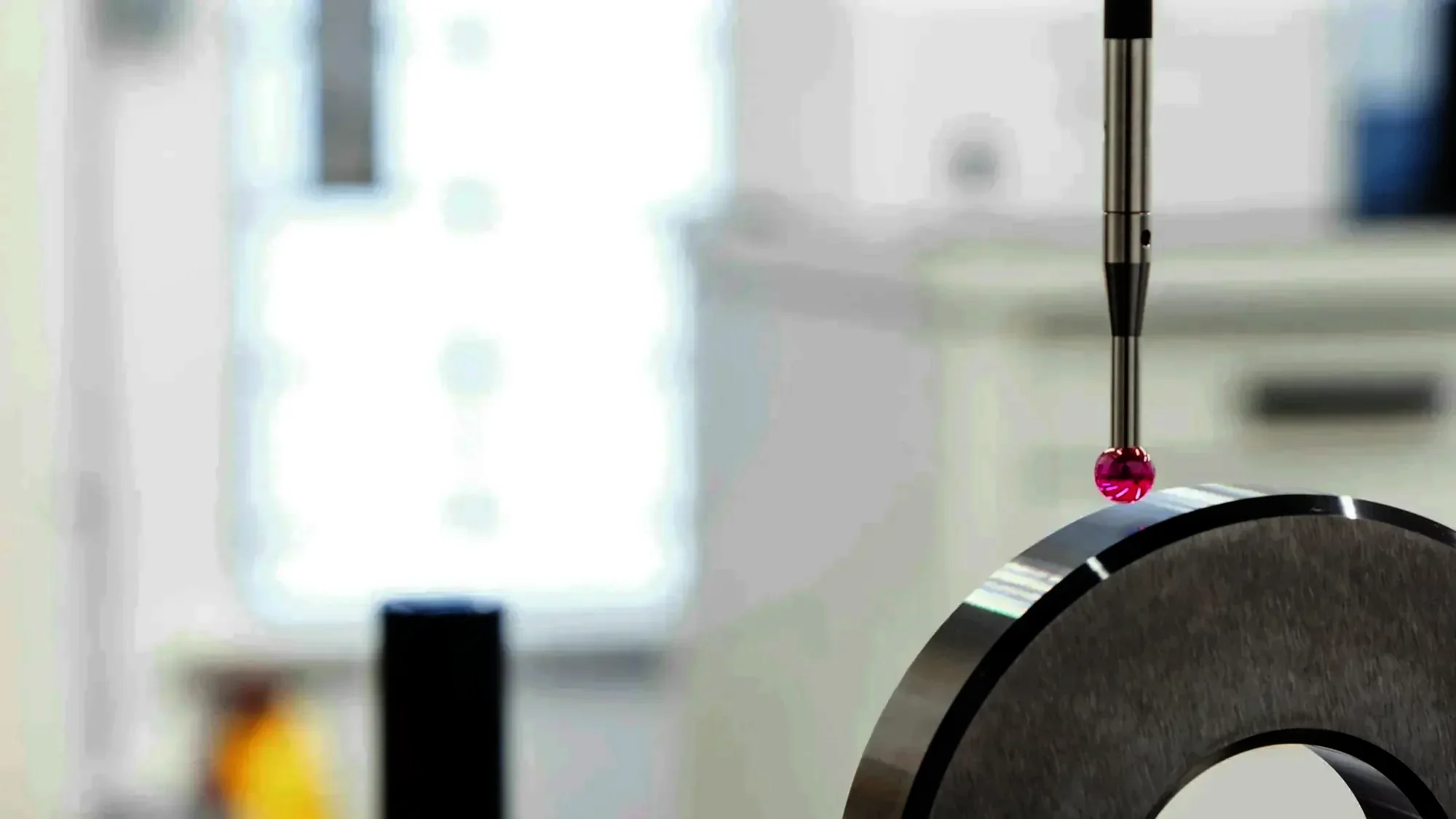 Ruby-tipped CMM probe touching a ground steel ring in a bright inspection room