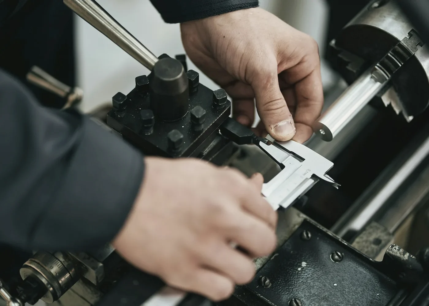 Hands measuring a part with a calliper at the machine