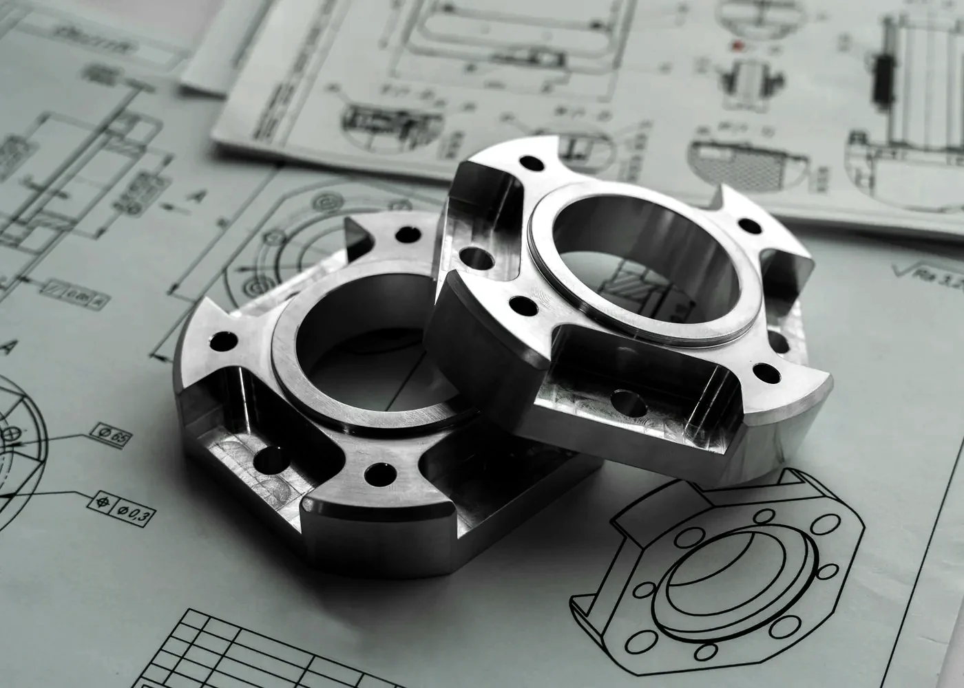 Two machined parts lying on an engineering drawing