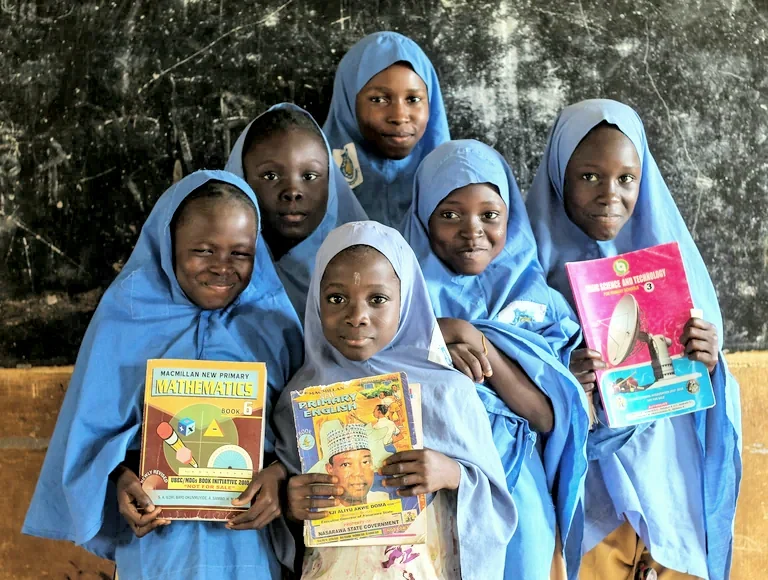 Five schoolgirls hold up their maths and science textbooks in class