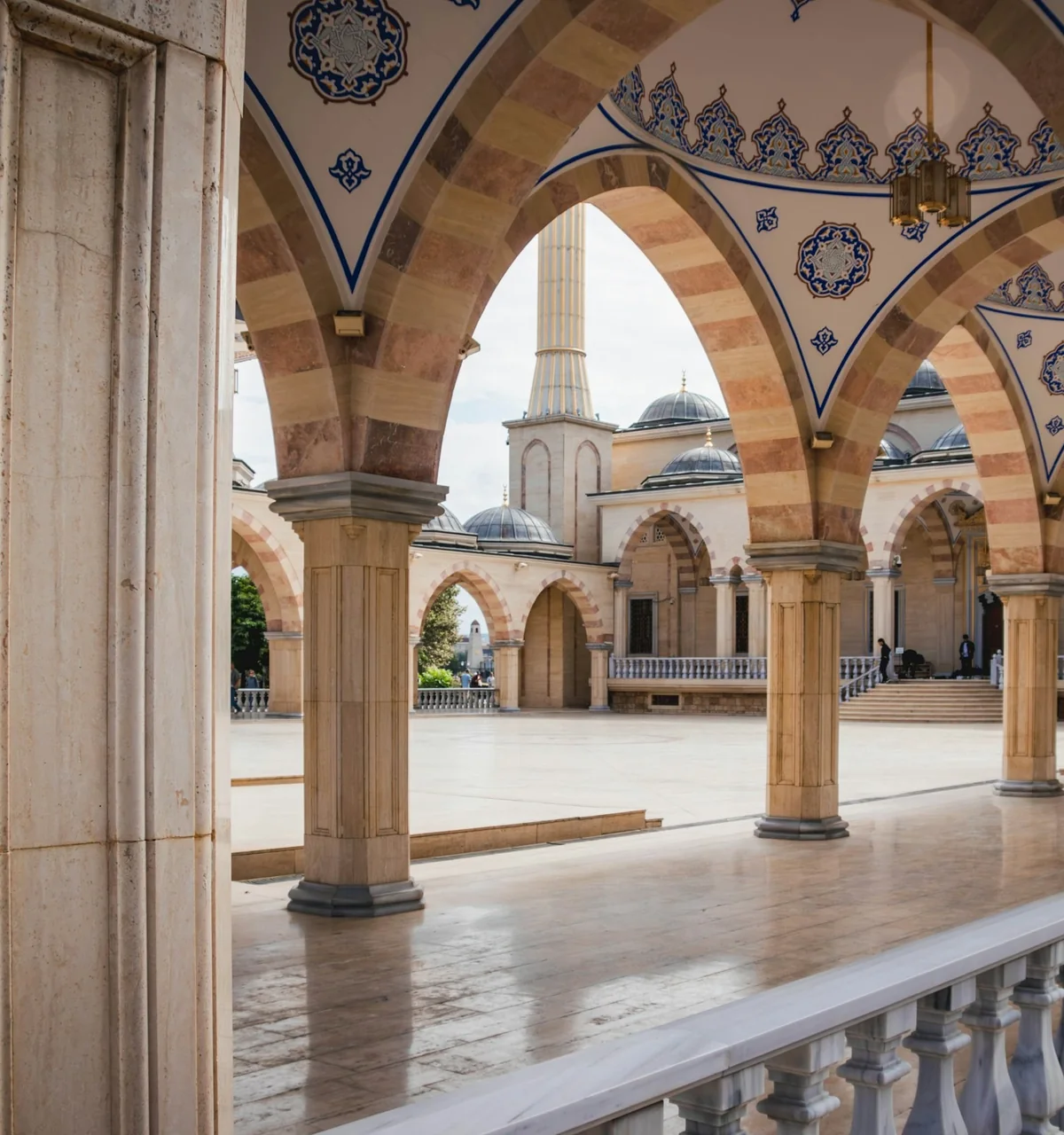 Sunlit stone arches and columns along a masjid colonnade