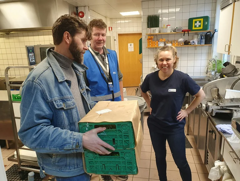 Pantry volunteers carry a crate of groceries through the community kitchen