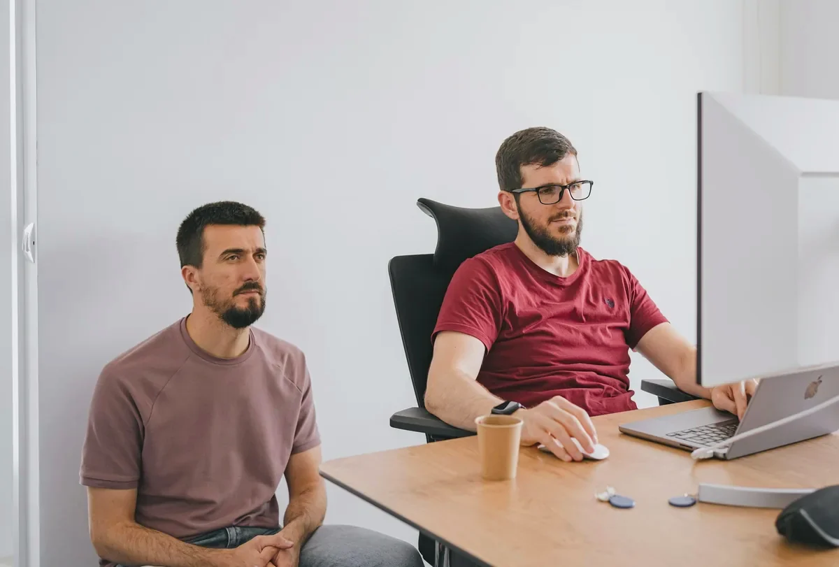Two investors listening to a founder's pitch at a desk in a bright office
