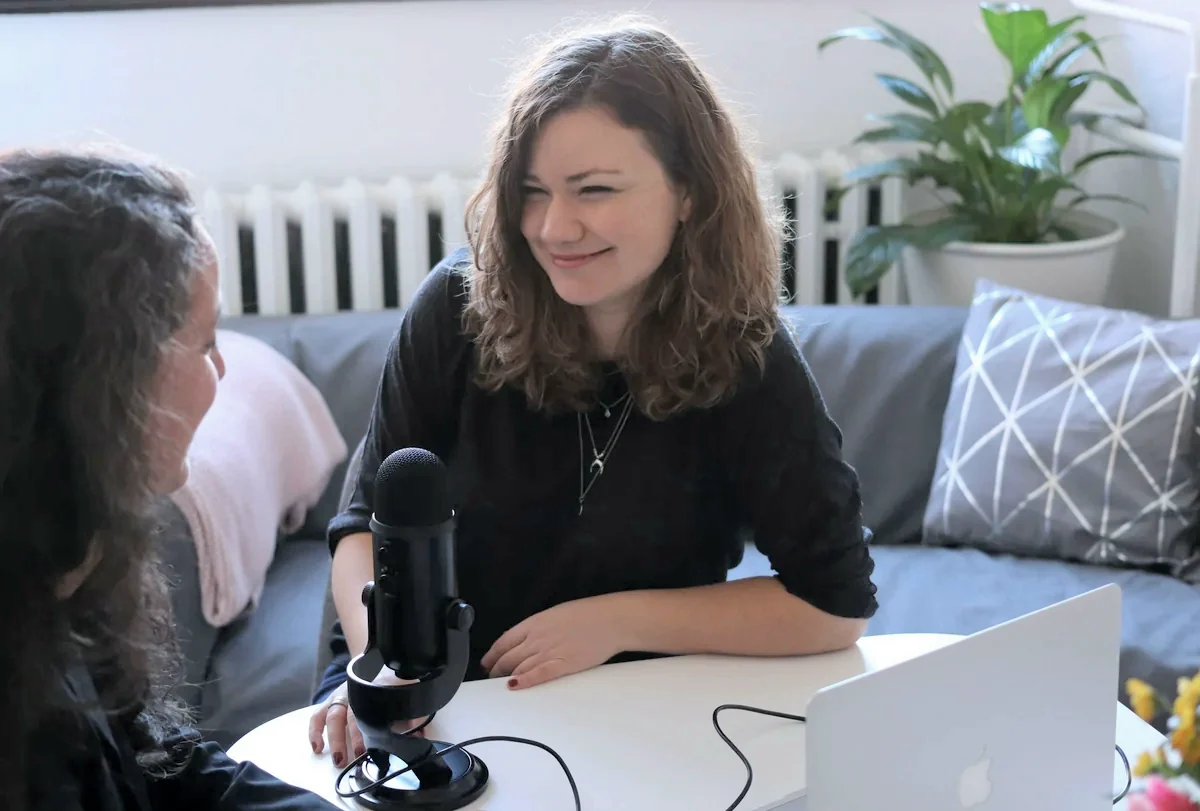 A founder being interviewed by a reporter at a table with a studio microphone
