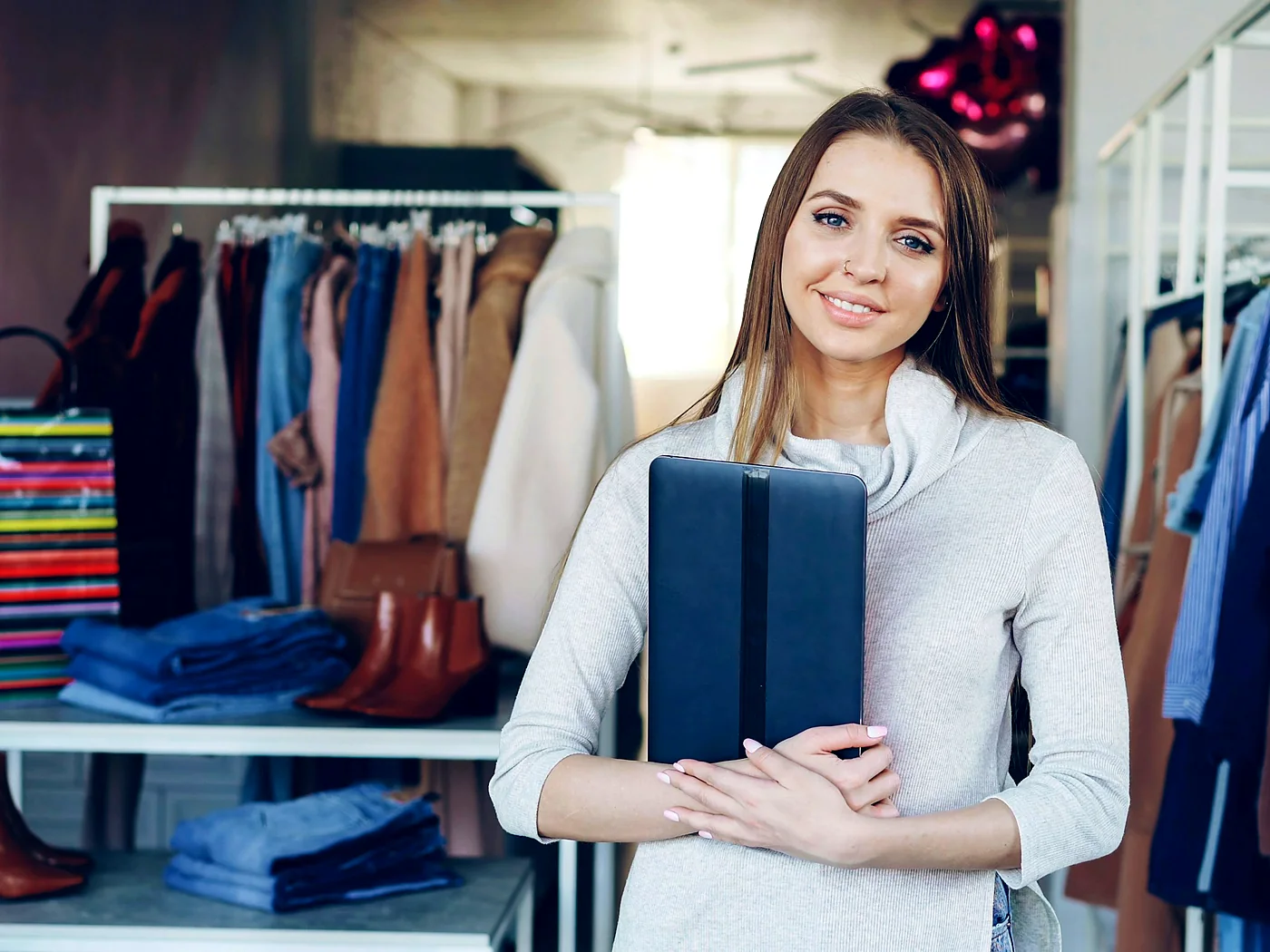 Fernway's store lead holding a tablet in the shop, rails of clothing behind her