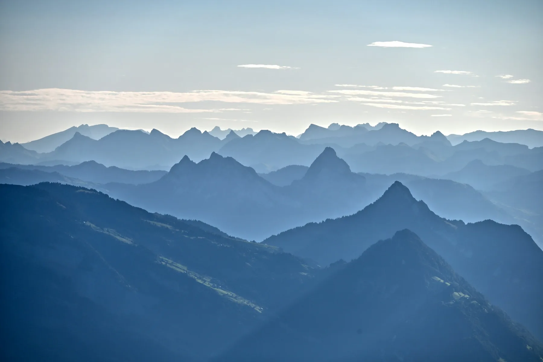 Layered steel-blue mountain ridges fading into morning haze