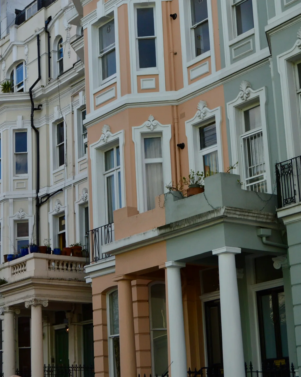Painted period terrace with bay windows, columns and iron railings in daylight