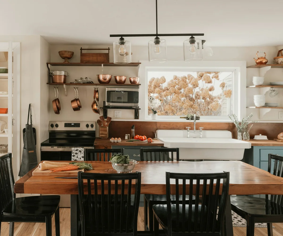 Kitchen in a period terrace with a long wooden table, copper pans and a wide window
