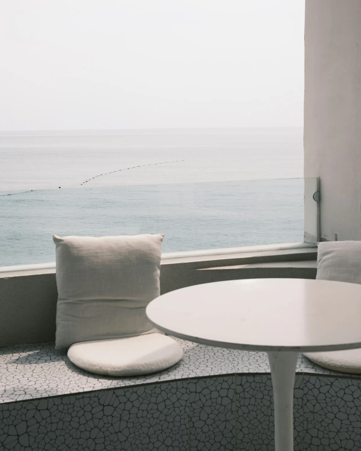 Hotel balcony with a white table and chair looking out to the sea