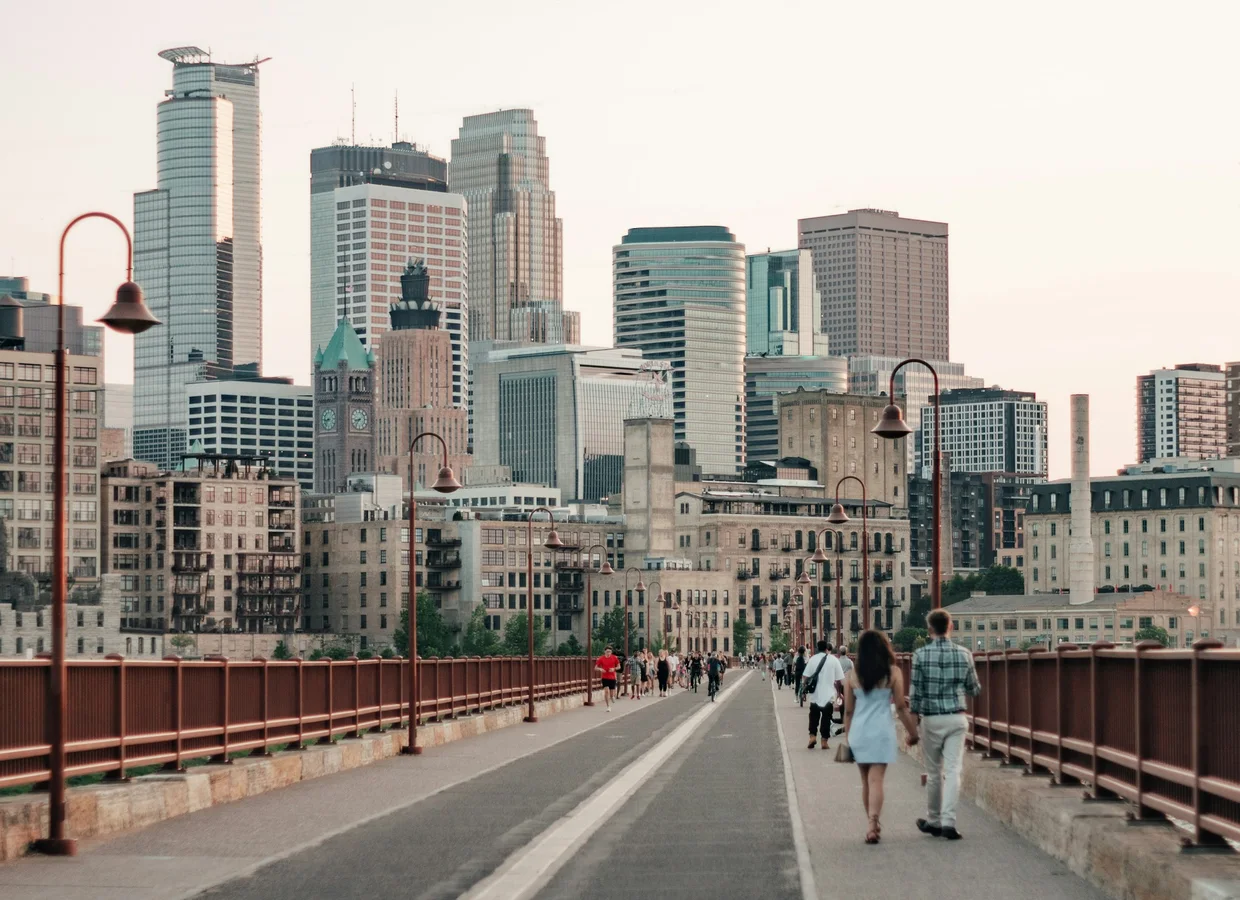 A couple walking hand in hand across the Stone Arch Bridge toward downtown Minneapolis