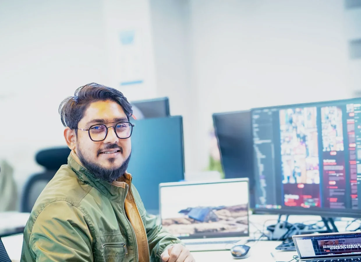 A software engineer smiling at his workstation in a bright office
