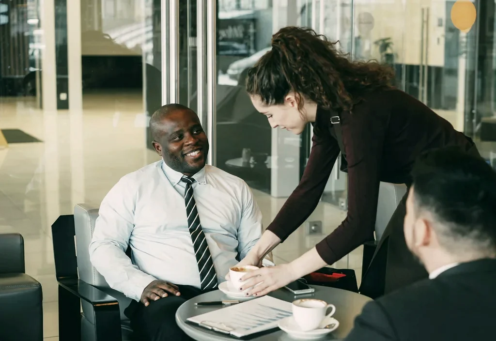 A smiling client in a shirt and tie talking through his case over coffee