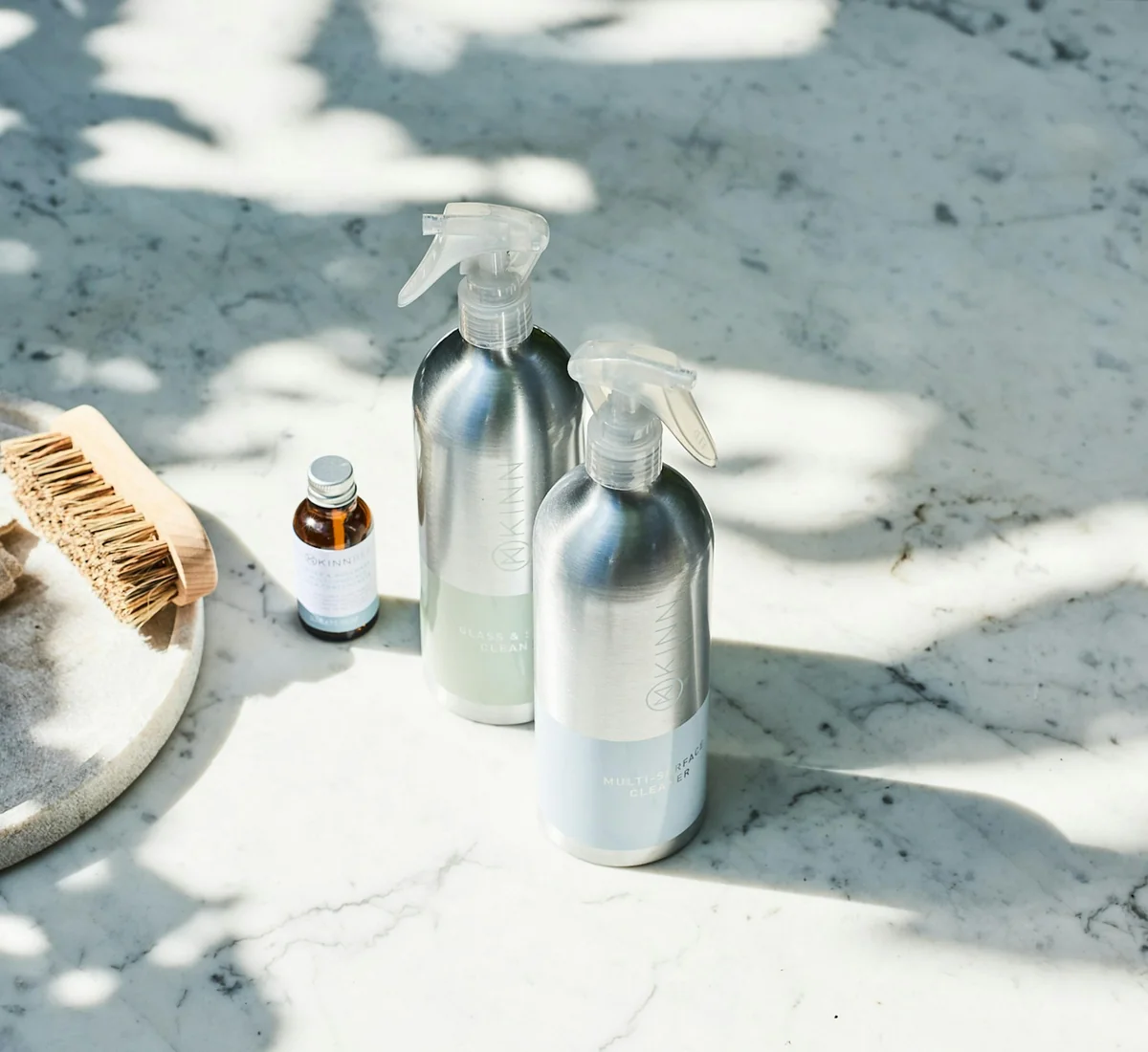 Refillable aluminium spray bottles and a natural brush in morning sun