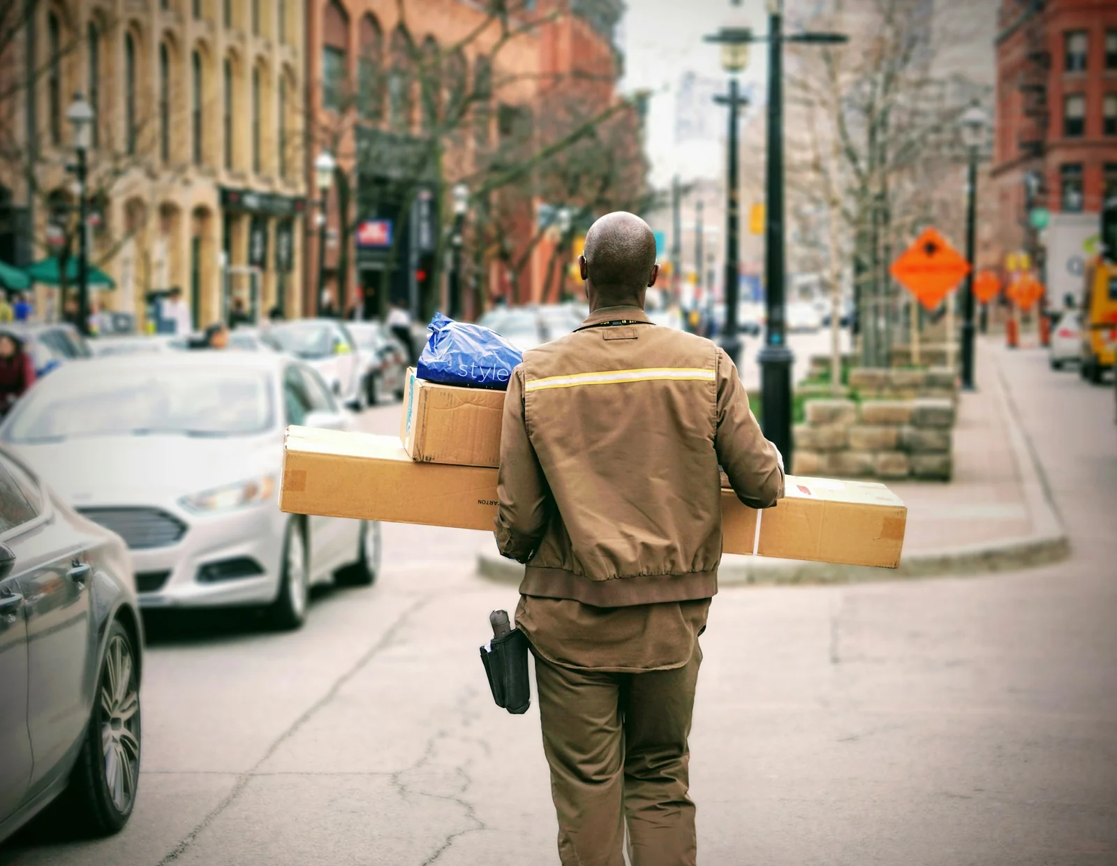 Courier carrying boxes along a busy city street